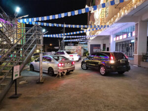 A black car approaching the parking spot in the middle of a silver sedan and White SUV at Xentro Mall Antipolo parking lot