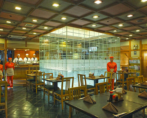 Waiters wearing red uniform and chefs wearing white while standing inside the Hatsu Hana Tei restaurant.